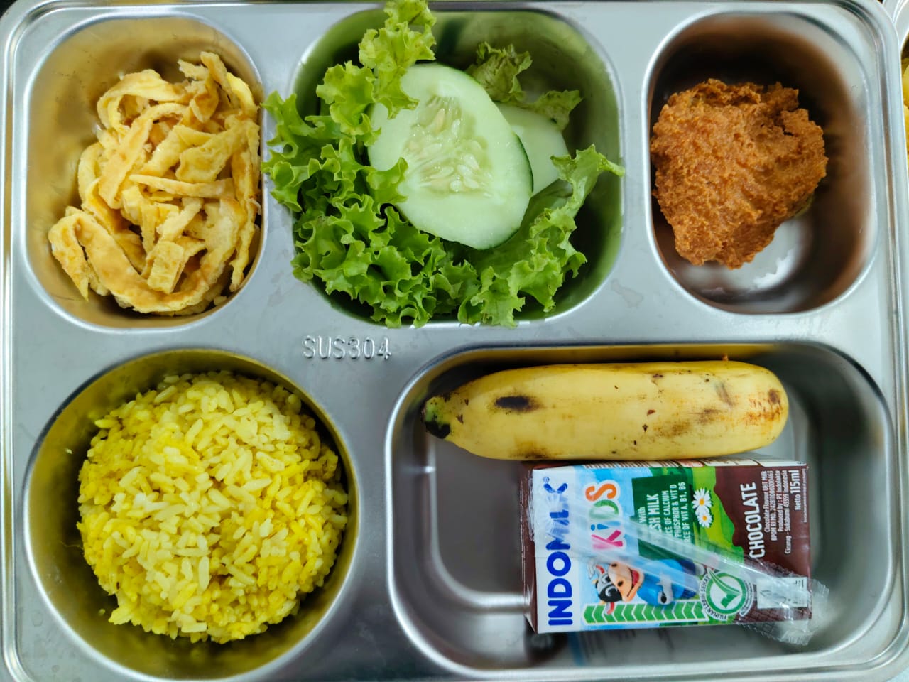 nasi goreng mentega, telur dadar suir, ayam crispy, sayur, pisang, susu kotak